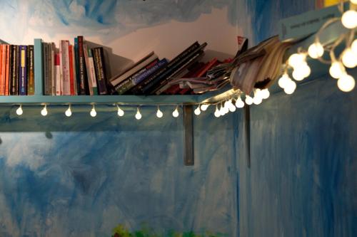 a shelf with a bunch of books and lights at Babelfish Hostel in Würzburg
