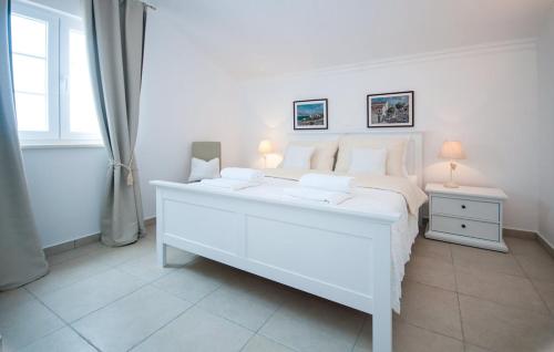 a white bedroom with a large white bed and a window at Villa Toma I in Novalja
