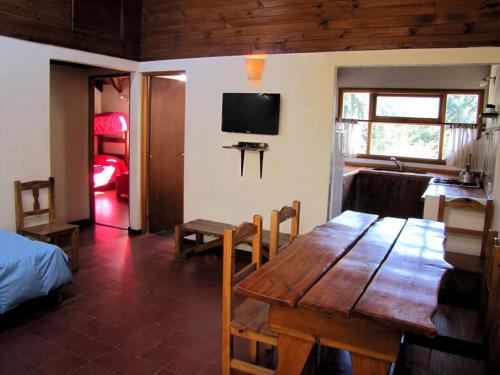 comedor con mesa de madera y TV en Hostel La Angostura en Villa La Angostura