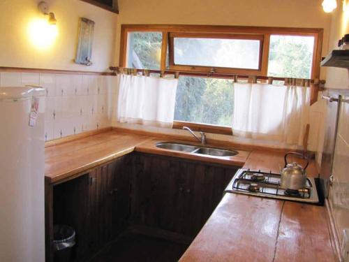 a kitchen with a sink and a stove and a window at Hostel La Angostura in Villa La Angostura