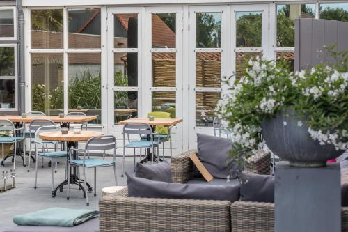 a patio with tables and chairs and a couch at De Herberg in Renesse