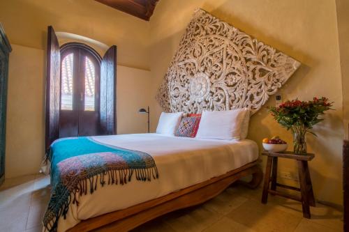 a bedroom with a bed with a large headboard at Casa El Carretero Hotel Boutique in Cartagena de Indias