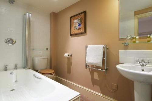a bathroom with a sink and a tub and a toilet at The Museum Inn in Farnham
