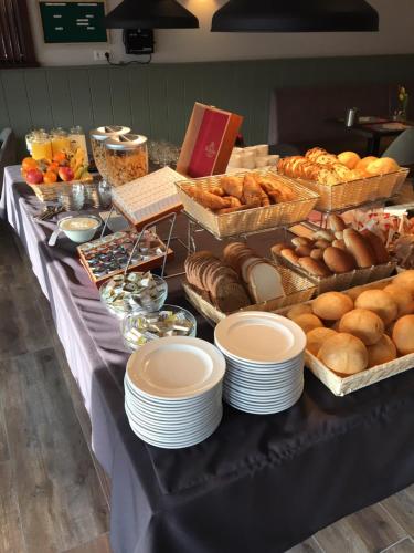 a table with plates and pastries and breads on it at Hotel bij Boone in Meliskerke