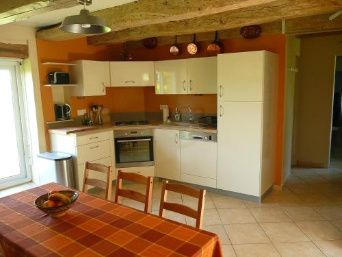uma cozinha com armários brancos e uma mesa com cadeiras em Domaine de Marsaguettes em Morlhon-le-Haut