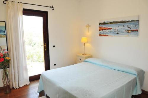 a white bedroom with a bed and a window at Villa Geron in San Teodoro