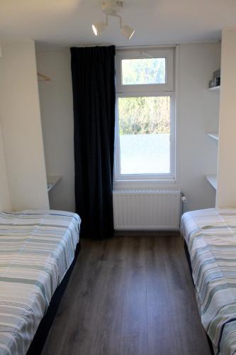 two beds in a room with a window at Houseboat Linquenda in Woubrugge