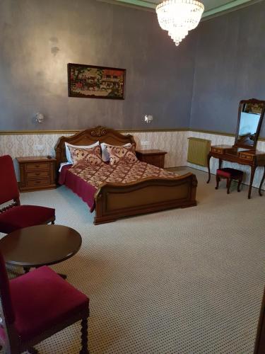 a bedroom with a bed and a chair and a table at NF Palace Old City Bucharest in Bucharest
