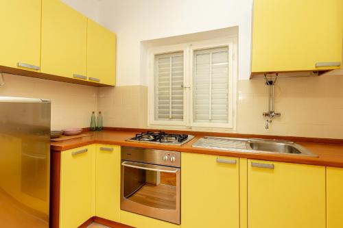 una cucina con mobili gialli, una stufa e un lavandino di Villa Misita a Dubrovnik