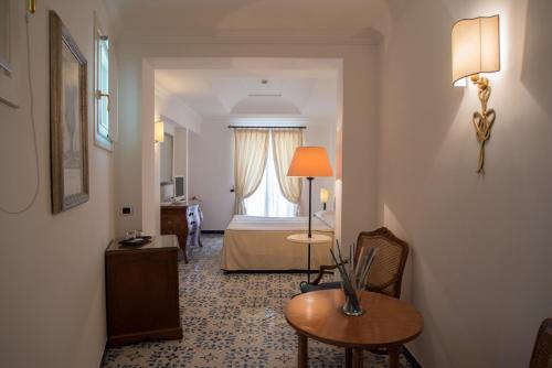 a hotel room with a bed and a table and chair at Hotel Posa Posa in Positano