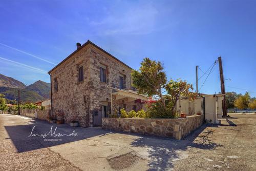 a stone building with a stone wall next to a street at Ianos Maisonette in Paralía Sergoúlas