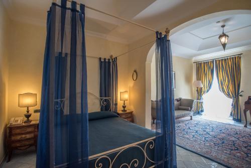 a bedroom with a canopy bed with blue curtains at Hotel Posa Posa in Positano