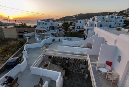 una persona sentada en un balcón con vistas a la puesta de sol en Pension Alexandra Mykonos port en Mykonos