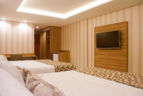 a hotel room with two beds and a flat screen tv at Paradiso Macae Hotel in Macaé
