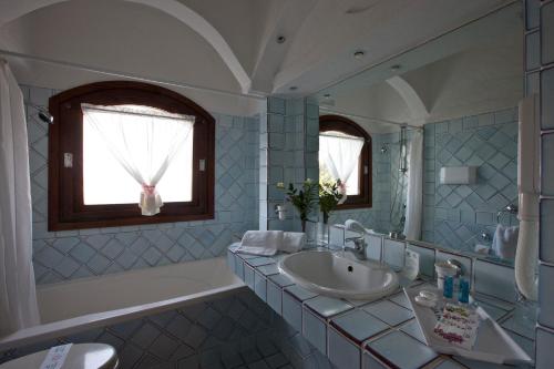 a bathroom with a sink and a tub and a mirror at Club Hotel Baja Sardinia in Baja Sardinia