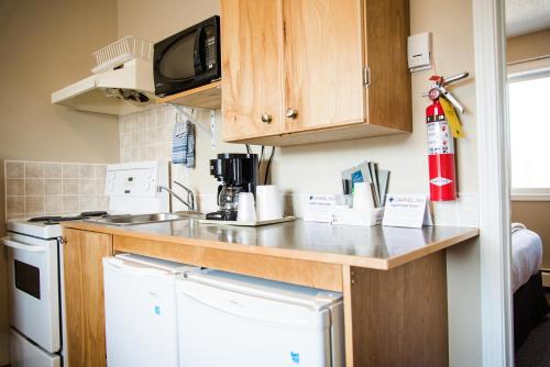 a kitchen with a counter and a sink and a dishwasher at Carmel Inn in Prince George