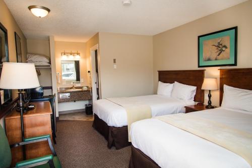 Pokój hotelowy z 2 łóżkami i biurkiem w obiekcie Carmel Inn w mieście Prince George