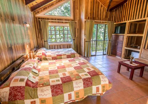 a bedroom with a bed in a room with windows at Sueños del Bosque Lodge in San Gerardo de Dota