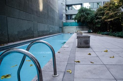 a swimming pool in a building with leaves on the ground at Austral Rentahome Diego de Velazquez in Santiago
