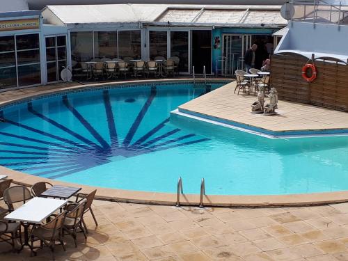 une grande piscine bleue avec des tables et des chaises dans l'établissement Magnifique Appartement CAP NATURISTE, au Cap d'Agde