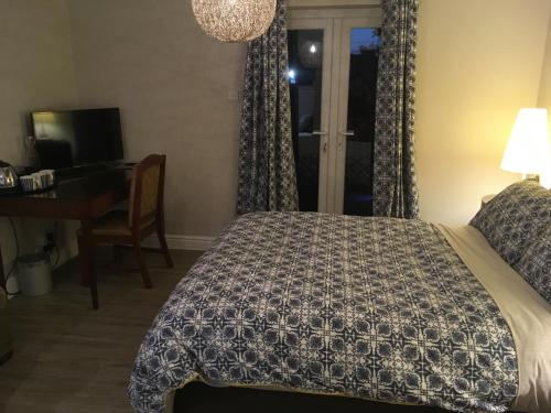 a bedroom with a bed and a desk and a window at The Annexe at Asbit Lodge in Mildenhall