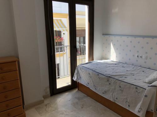 サンルーカル・デ・バラメダにあるSanlucar Iのベッドルーム1室(ベッド1台付)、バルコニーへのドアが備わります。