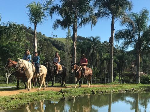 a group of people riding horses by a pond at Pousada das Hortênsias in São Bonifácio