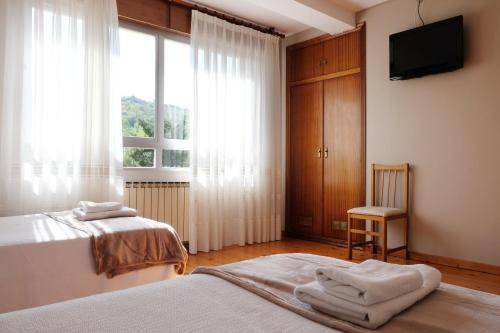 1 dormitorio con 2 camas, TV y ventana en La Terraza de Picos en Ortiguero