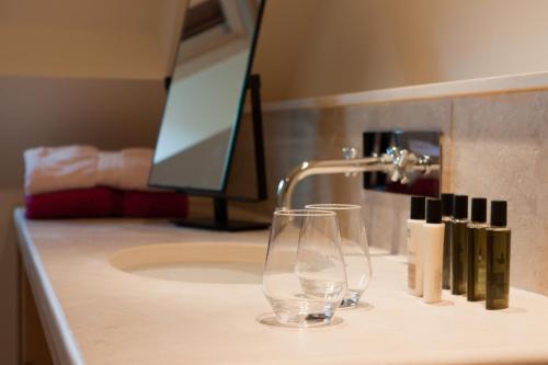 a bathroom sink with a drinking glass and a faucet at Appart'hôtels La Maison du Tigre in Stutzheim