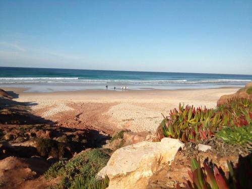 a beach with people walking on the sand and the ocean at Urban Art by Campigir in Peniche