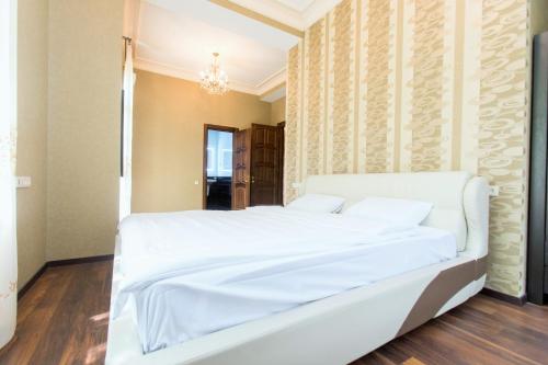 a bedroom with a white bed and a chandelier at Villa Garden in Tbilisi City