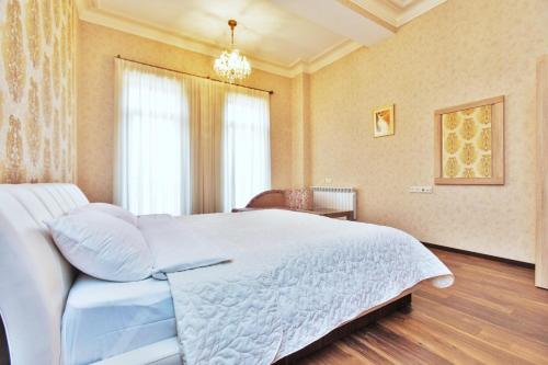 a bedroom with a large white bed and a chandelier at Villa Garden in Tbilisi City