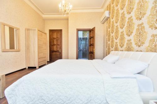 a bedroom with a large white bed and a chandelier at Villa Garden in Tbilisi City