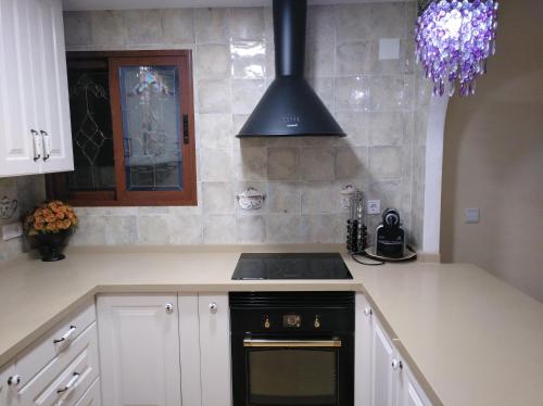 a kitchen with white cabinets and a black stove top oven at Precioso chalet en la playa de Tavernes de la Valldigna in Tavernes de Valldigna
