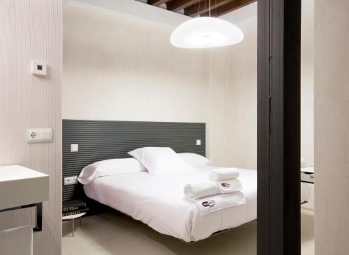 a bedroom with a white bed with a black headboard at Antidoto Rooms San Agustín - Recomendado para adultos in Toledo