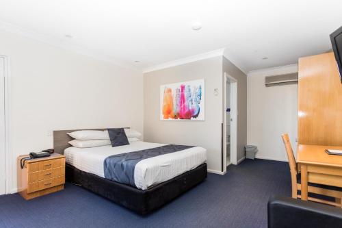 a bedroom with a bed and a desk and a computer at West End Motor Lodge in Orange