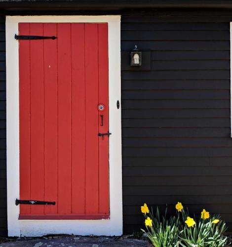 a red door on a black house with flowers at Squire Tarbox Inn in Westport