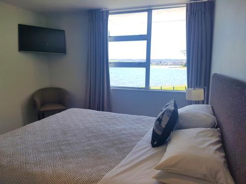 a bedroom with a bed with a large window at Waimahana Apartment 4 in Taupo