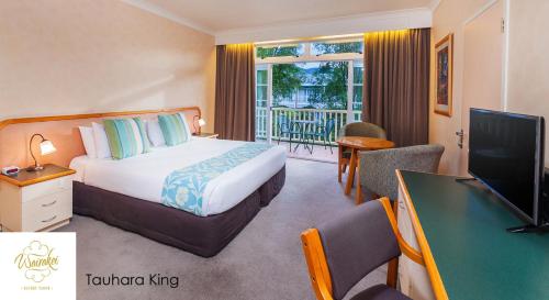 a hotel room with a bed and a desk and a television at Wairakei Resort Taupo in Taupo