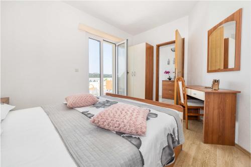 Schlafzimmer mit einem Bett mit rosa Kissen und einem Schreibtisch in der Unterkunft Apartments Petranić in Tisno