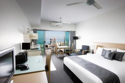 a hotel room with a bed and a desk with a television at Mantra Pandanas in Darwin