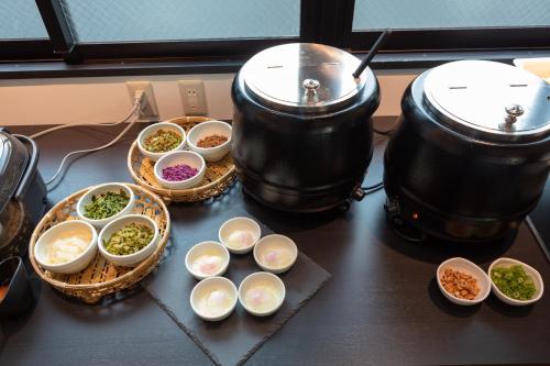 a table with two pots and bowls of different types of food at Ariston Hotel Kyoto Jujo in Kyoto