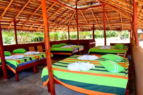 a group of four beds under a straw umbrella at Rivosen Camp Yala Safari in Yala