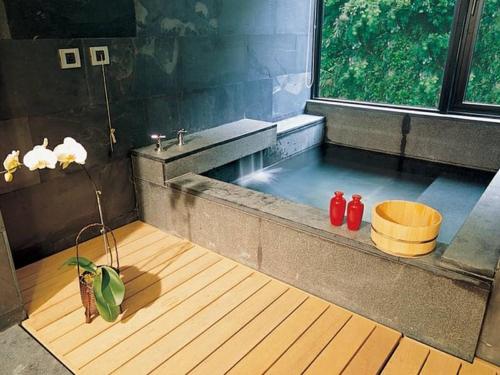 ein Badezimmer mit einer Badewanne und zwei roten Flaschen in der Unterkunft Volando Urai Spring Spa & Resort in Wulai