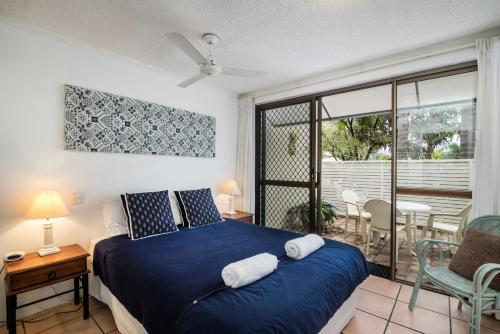 a bedroom with a blue bed and a balcony at Sunseeker Holiday Apartments in Sunshine Beach