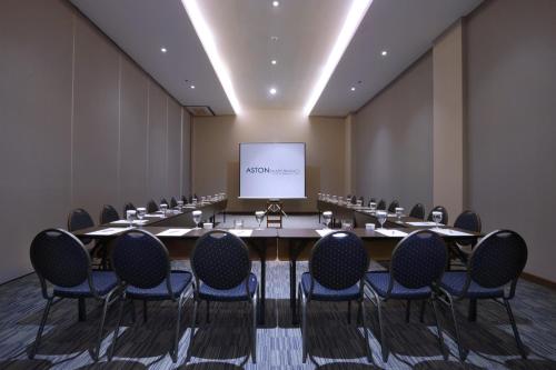 a conference room with a table and chairs and a screen at Aston Banyuwangi Hotel and Conference Center in Banyuwangi