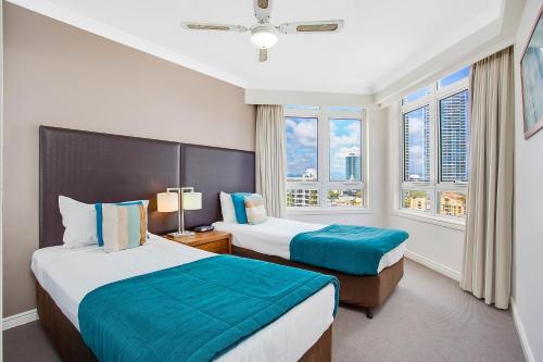 Una habitación de hotel con dos camas y dos ventanas. en BreakFree Moroccan, en Gold Coast
