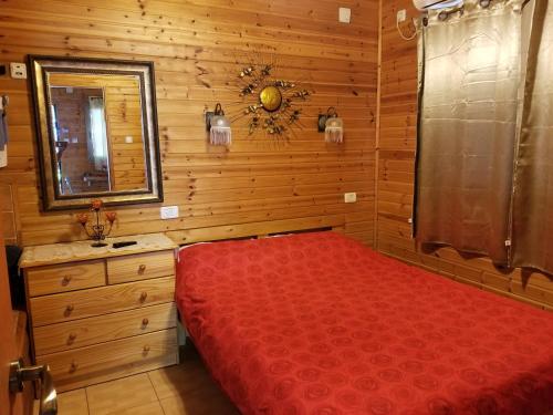 a bedroom with a red bed and a mirror at kinneret love sounds in Migdal