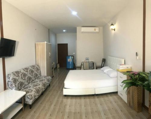 a bedroom with a white bed and a couch at Tamruethai House - ตามฤทัยเฮาส์ in Chiang Mai