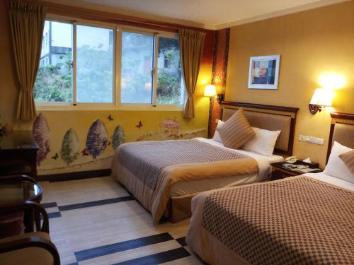 ein Hotelzimmer mit zwei Betten und einem Fenster in der Unterkunft Puti Commercial Hotel in Longtan